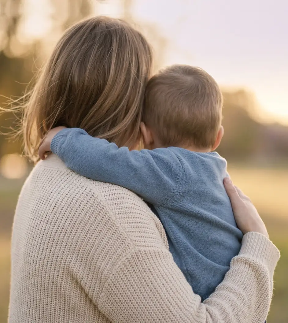 Frau hält ein Kind schützend im Arm